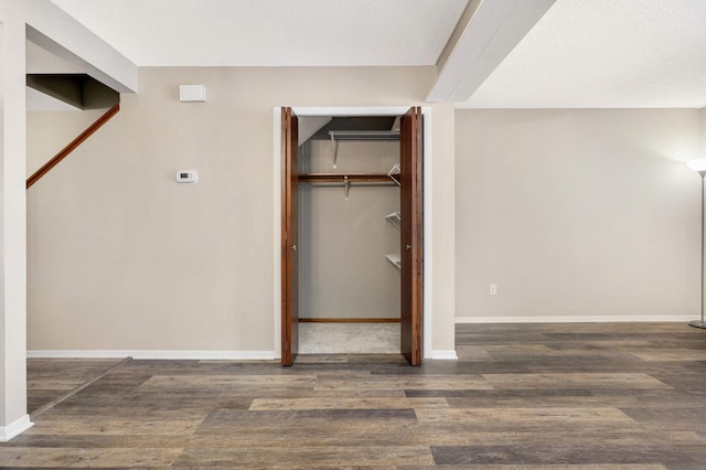 unfurnished bedroom with a textured ceiling, dark hardwood / wood-style flooring, and a closet