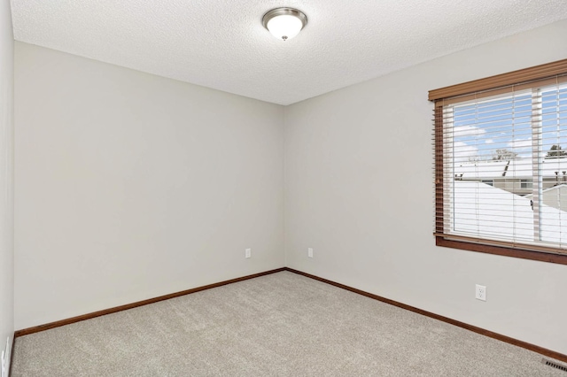 carpeted empty room featuring a textured ceiling