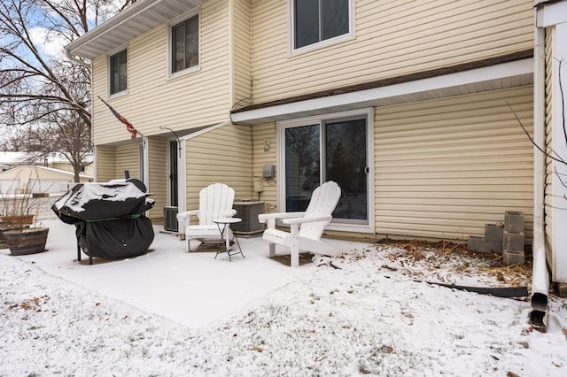 snow covered patio featuring central AC unit and area for grilling