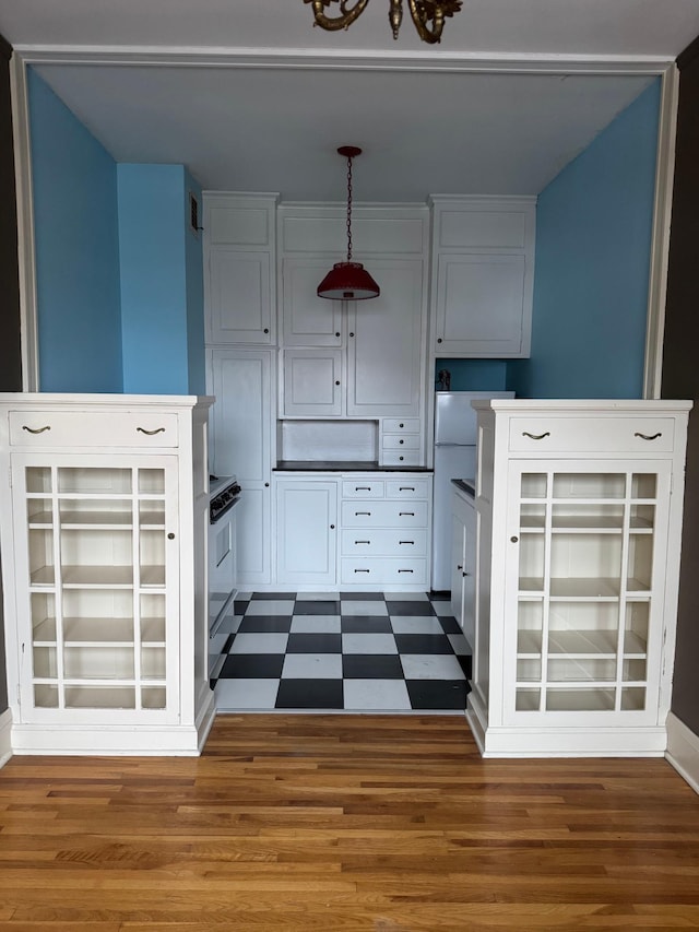 kitchen with white cabinets, wood-type flooring, and decorative light fixtures