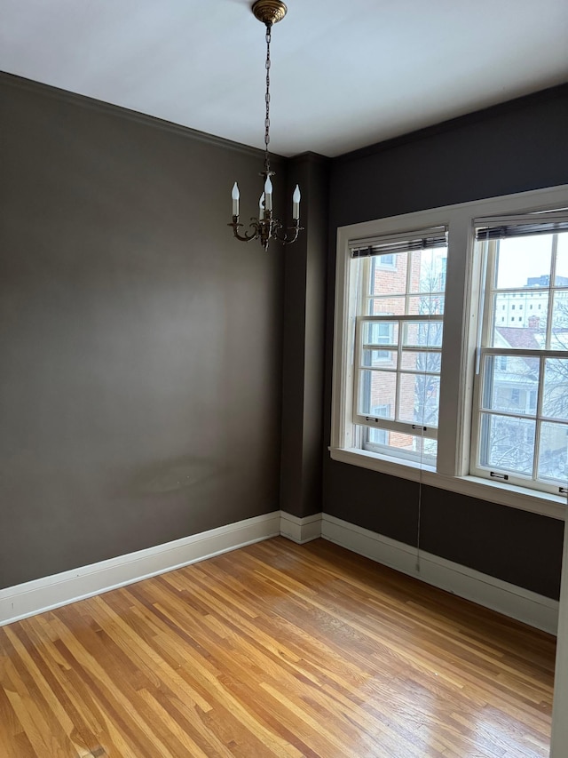 unfurnished room featuring crown molding, light hardwood / wood-style floors, and a notable chandelier