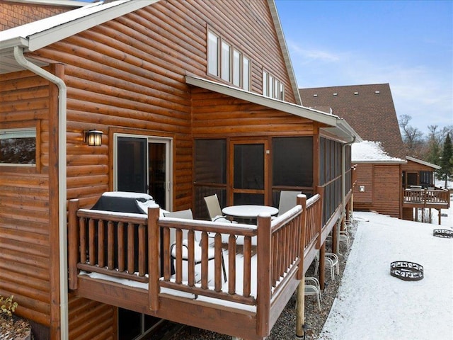 snow covered deck featuring a sunroom