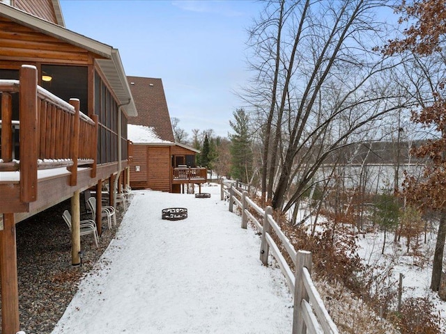 yard layered in snow with a sunroom, a fire pit, and a deck