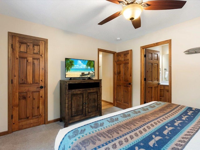 bedroom with ceiling fan, light colored carpet, and connected bathroom