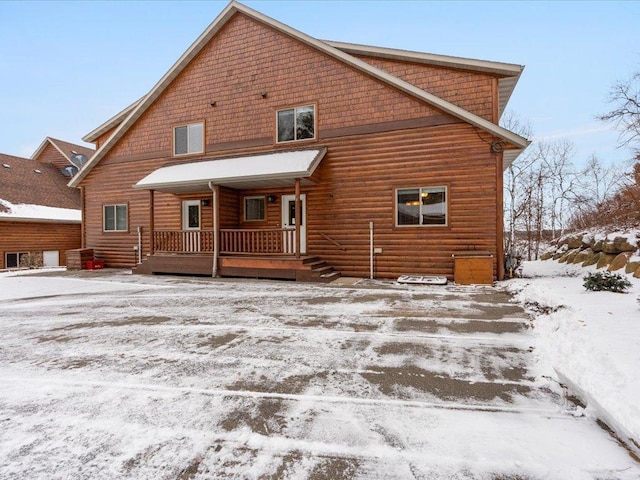 snow covered rear of property with a porch