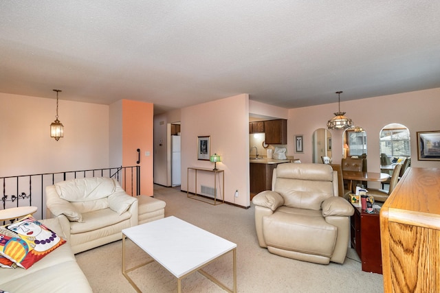 living room with sink, light colored carpet, and a textured ceiling