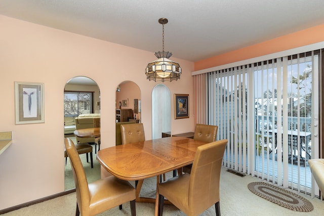 dining area featuring a textured ceiling, light colored carpet, and a notable chandelier