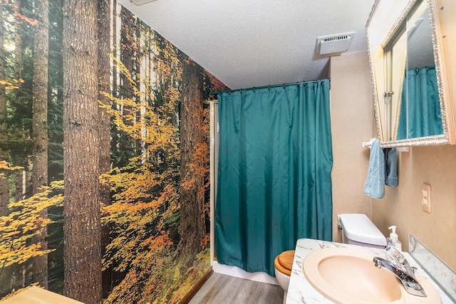 bathroom featuring sink, toilet, a textured ceiling, curtained shower, and wood-type flooring