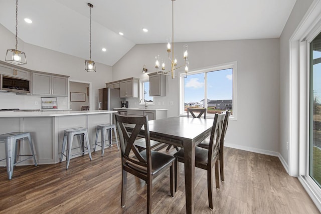 dining room with hardwood / wood-style floors, a notable chandelier, lofted ceiling, and sink