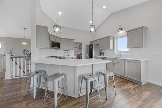 kitchen featuring kitchen peninsula, appliances with stainless steel finishes, decorative light fixtures, and gray cabinetry