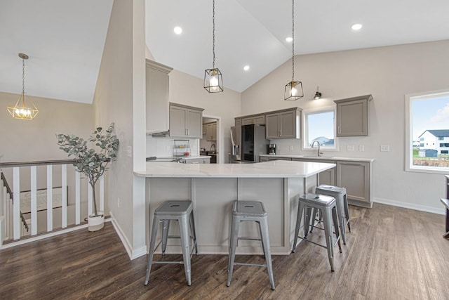 kitchen with kitchen peninsula, stainless steel refrigerator with ice dispenser, pendant lighting, and sink