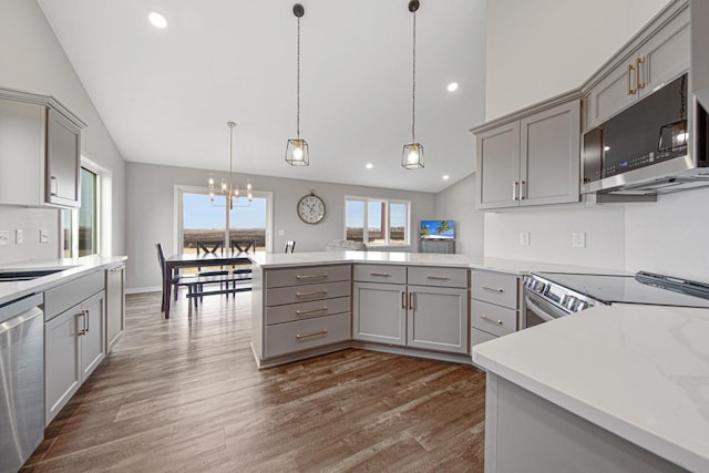 kitchen featuring gray cabinetry, kitchen peninsula, stainless steel appliances, and vaulted ceiling