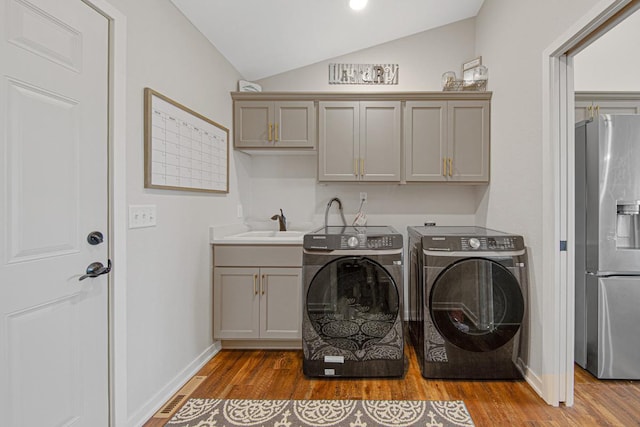 laundry room with washer and clothes dryer, sink, cabinets, and hardwood / wood-style floors