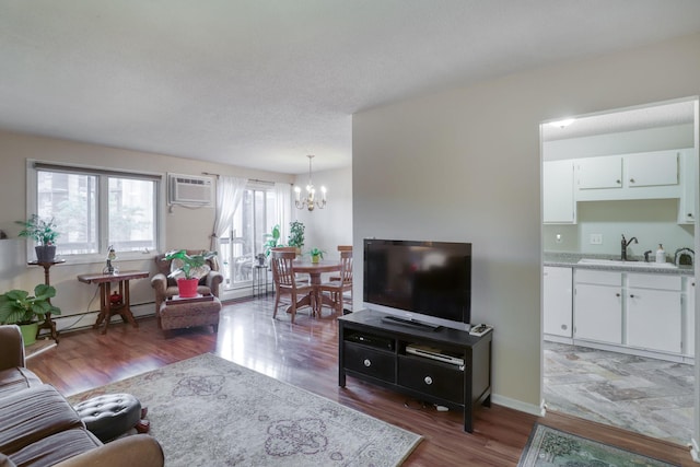 living room with a wall unit AC, dark hardwood / wood-style flooring, sink, and an inviting chandelier