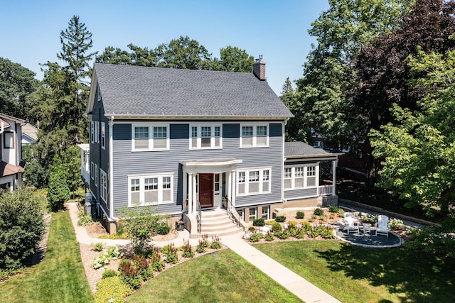 view of front of house featuring a shingled roof, a chimney, and a front yard