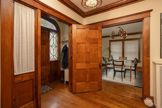 entrance foyer with an inviting chandelier, radiator heating unit, ornamental molding, and dark wood finished floors