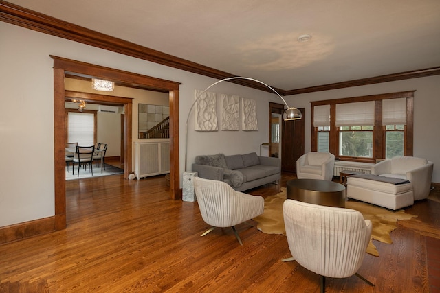 living area featuring stairs, crown molding, baseboards, and wood finished floors