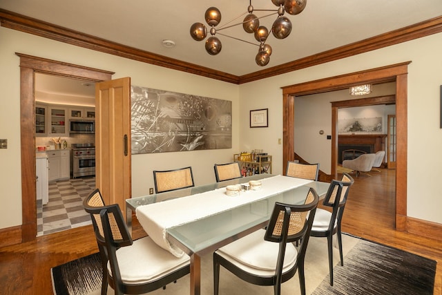 dining room featuring light wood-style floors, a fireplace, ornamental molding, and a notable chandelier