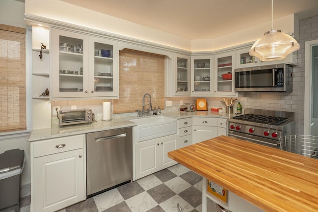 kitchen featuring stainless steel appliances, dark floors, a sink, and decorative backsplash