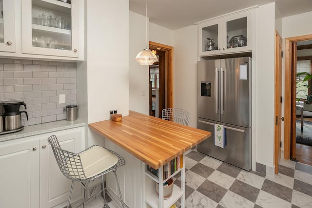 kitchen featuring light floors, tasteful backsplash, glass insert cabinets, white cabinetry, and stainless steel fridge with ice dispenser