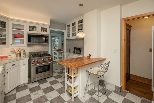 kitchen featuring light floors, tasteful backsplash, appliances with stainless steel finishes, glass insert cabinets, and white cabinetry