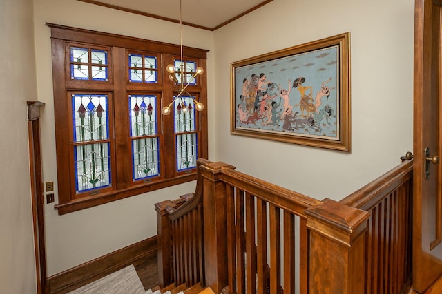 stairway featuring crown molding, a notable chandelier, wood finished floors, and baseboards