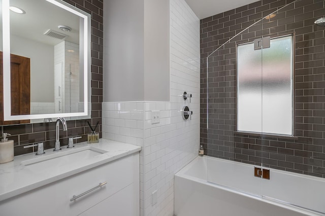 full bathroom featuring visible vents, tile walls, vanity, and bathing tub / shower combination