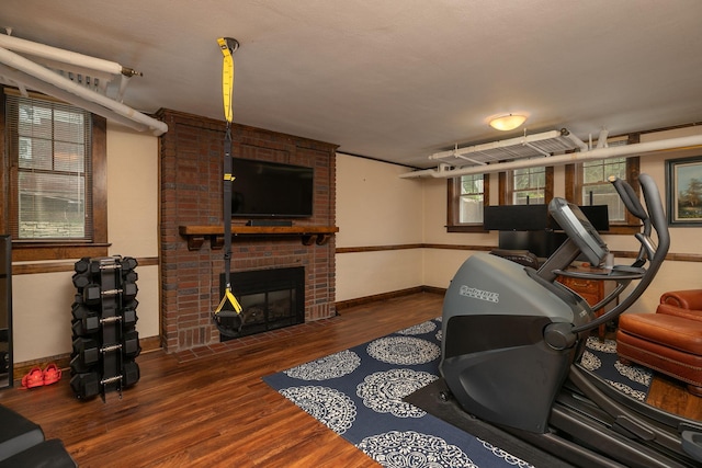 exercise area featuring a fireplace, baseboards, and wood finished floors