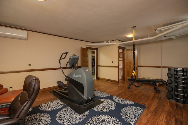 exercise area with baseboards, wood finished floors, and a wall mounted AC