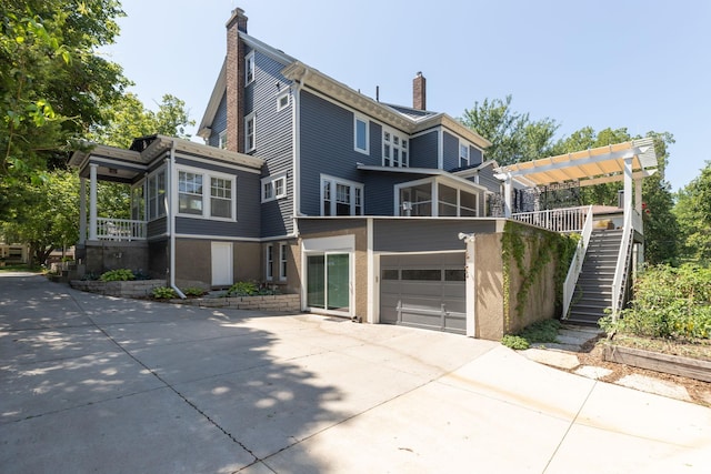 exterior space with a garage, concrete driveway, a chimney, and a sunroom