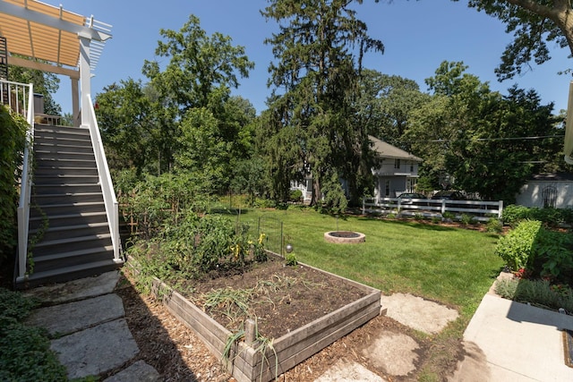 view of yard featuring stairs, a pergola, a vegetable garden, and fence