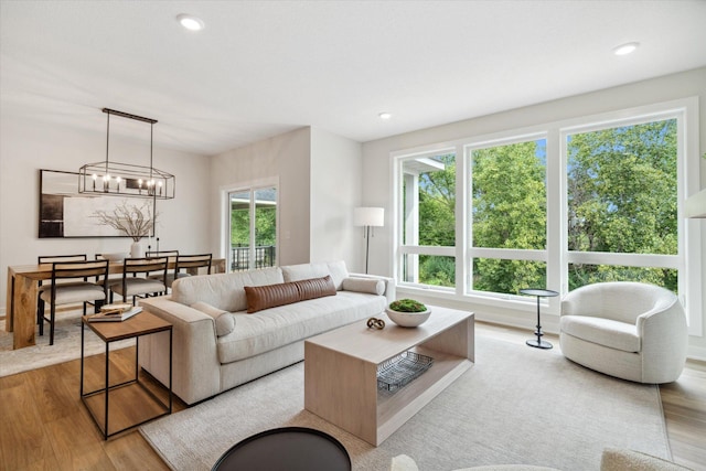 living room with an inviting chandelier, light hardwood / wood-style flooring, and a healthy amount of sunlight