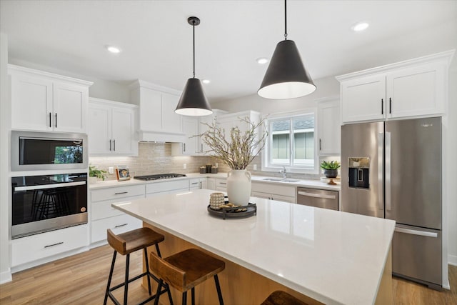 kitchen featuring white cabinets, a center island, sink, and appliances with stainless steel finishes