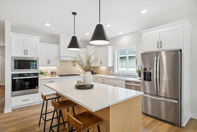 kitchen featuring white cabinets, light wood-type flooring, a center island, and stainless steel appliances