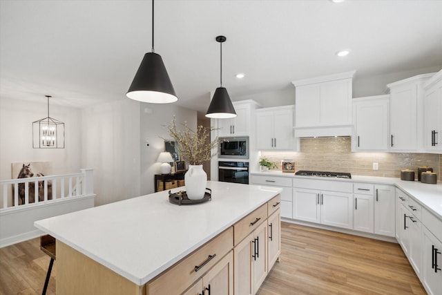 kitchen featuring white cabinets, stainless steel appliances, a kitchen island, and light hardwood / wood-style floors