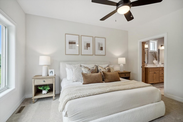 carpeted bedroom featuring connected bathroom, multiple windows, and ceiling fan