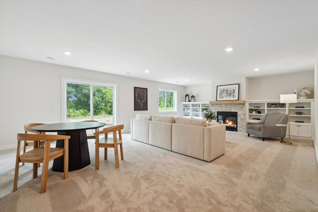 carpeted living room with a stone fireplace