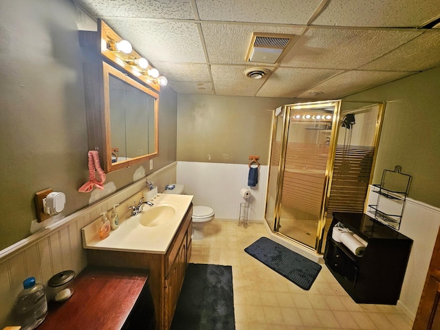 full bath with a paneled ceiling, a wainscoted wall, a shower stall, and visible vents