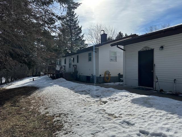 snow covered house featuring a chimney and a deck