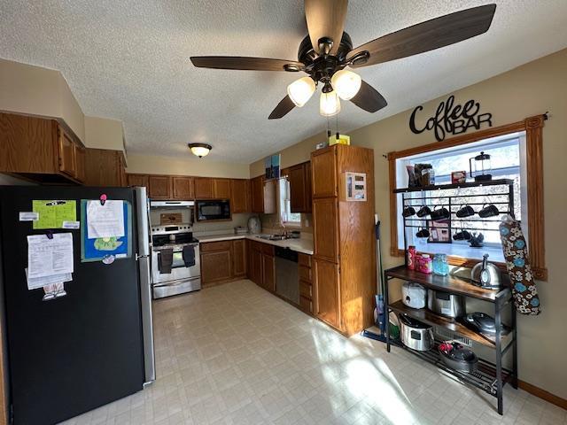 kitchen featuring brown cabinets, light floors, stainless steel appliances, light countertops, and a sink