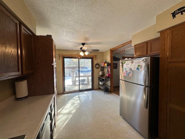 kitchen featuring light floors, light countertops, a ceiling fan, freestanding refrigerator, and dishwashing machine