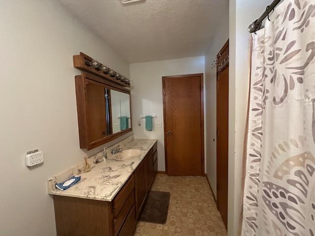 bathroom featuring a textured ceiling, curtained shower, vanity, and tile patterned floors