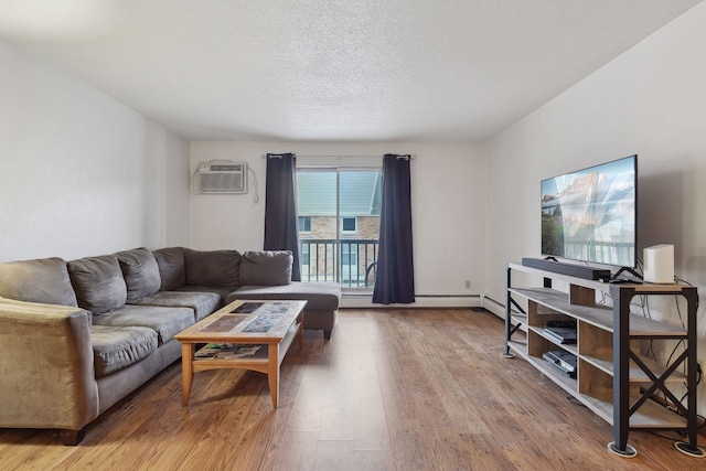 living room featuring wood-type flooring, a wall unit AC, and a textured ceiling