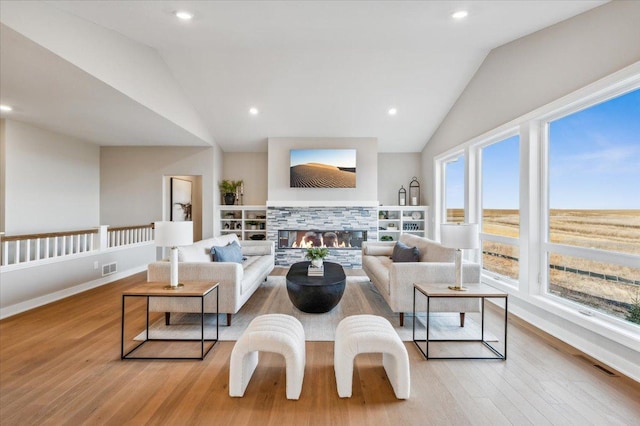 living room with a tile fireplace, light wood-type flooring, and vaulted ceiling