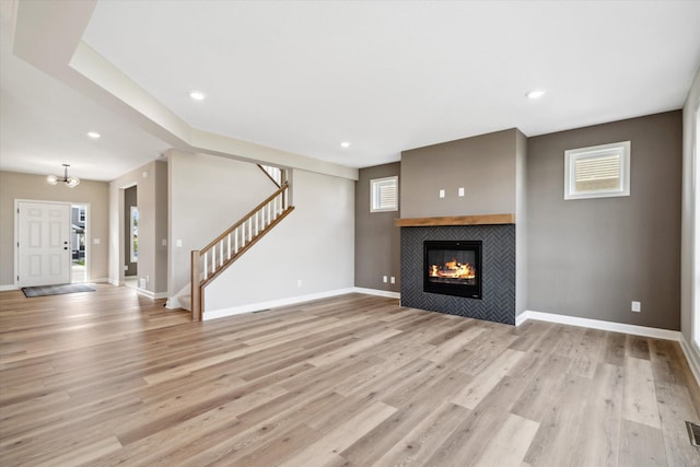 unfurnished living room featuring a tile fireplace, plenty of natural light, and light hardwood / wood-style floors