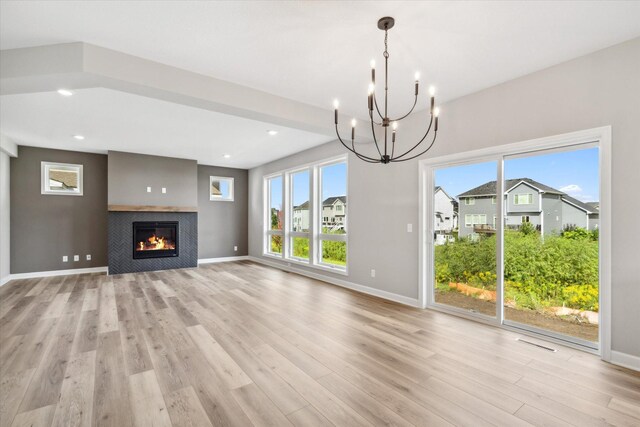 unfurnished living room featuring a tile fireplace, light hardwood / wood-style floors, and an inviting chandelier