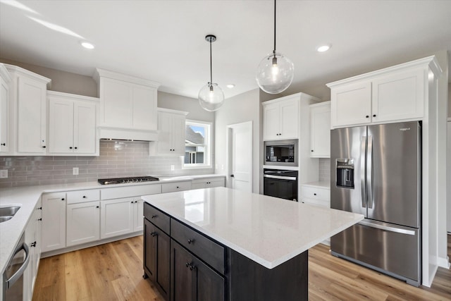 kitchen featuring black appliances, pendant lighting, white cabinets, and light hardwood / wood-style floors