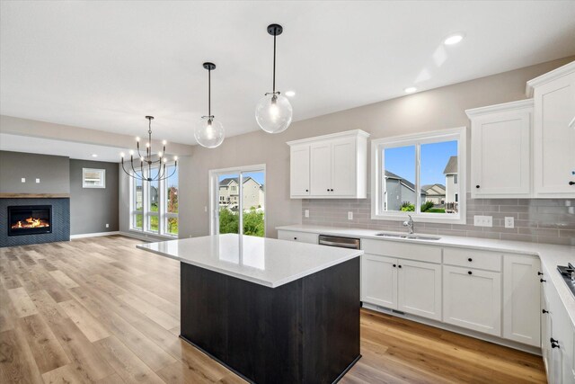 kitchen with sink, decorative light fixtures, a center island, white cabinetry, and plenty of natural light