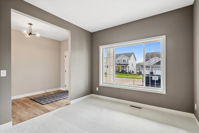 unfurnished room with hardwood / wood-style flooring and an inviting chandelier