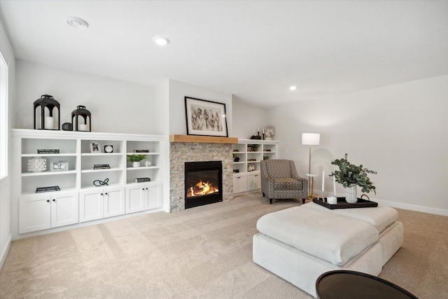 carpeted living room featuring a stone fireplace